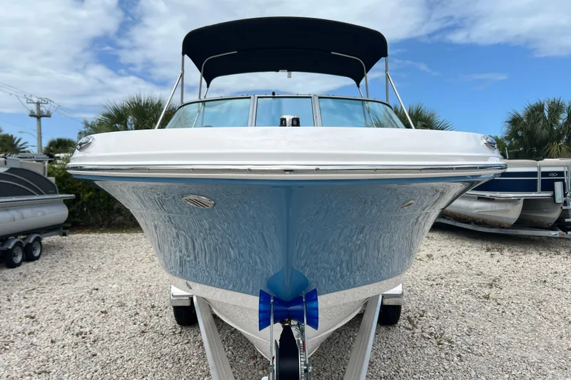 Slide: The Image of 2026 Robalo R207 Dual Console boat with blue hull, parked on gravel lot. - 7