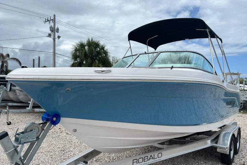 Slide: The Image of 2026 Robalo R207 Dual Console boat on trailer, blue hull, under cloudy sky. - 8