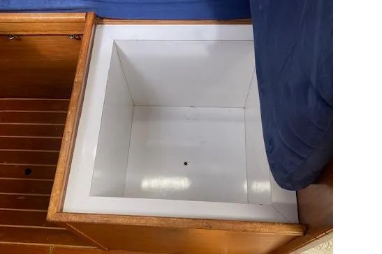 Slide: The Image of Storage compartment on 1983 Wauquiez 38 sailboat, featuring wooden trim and blue upholstery. - 10