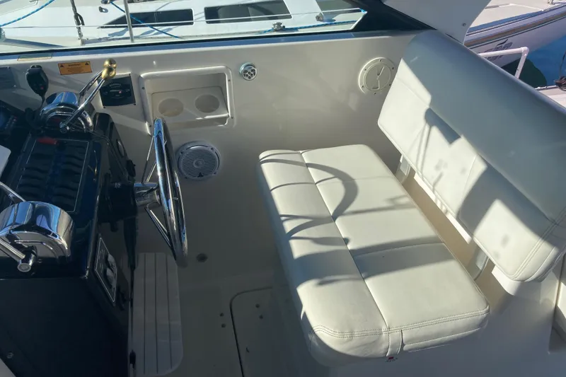 Slide: The Image of 2002 Tiara Yachts 2900 Open helm with white seating and steering wheel. - 47