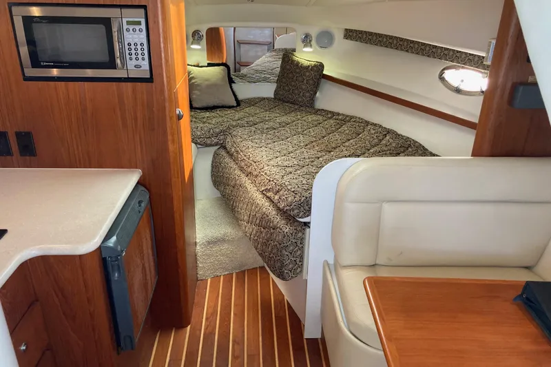 Slide: The Image of Interior of a 2002 Tiara Yachts 2900 Open, featuring a cozy cabin with a bed and kitchenette. - 56