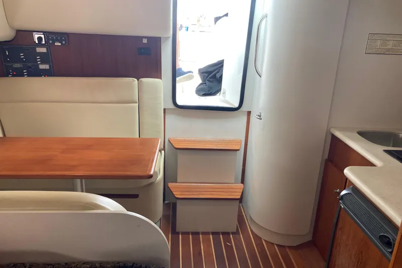 Slide: The Image of Interior of 2002 Tiara Yachts 2900 Open, featuring seating, table, and compact kitchen area. - 58