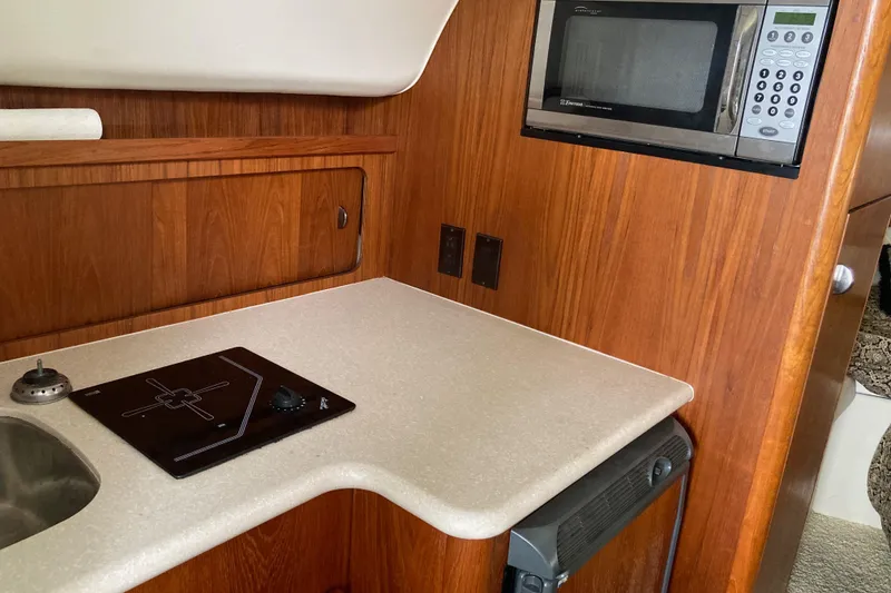 Slide: The Image of 2002 Tiara Yachts 2900 Open galley with microwave, cooktop, and wooden cabinetry. - 60