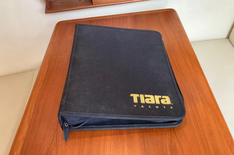 Slide: The Image of Black Tiara Yachts folder on wooden table, related to 2002 Tiara Yachts 2900 Open model. - 62