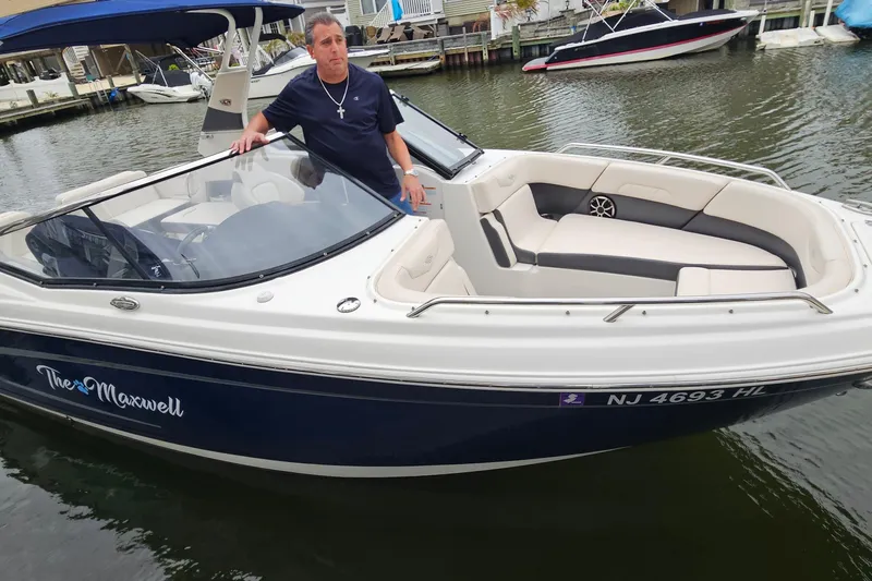 Slide: The Image of Man standing on 2018 Chaparral 257 SSX boat named "The Maxwell" docked in marina. - 18