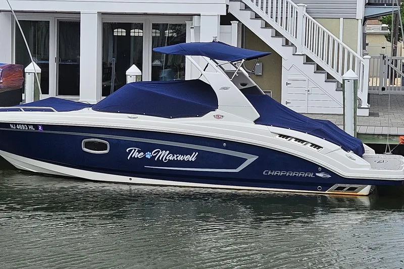 Slide: The Image of 2018 Chaparral 257 SSX boat docked with blue cover and custom name "The Maxwell." - 2