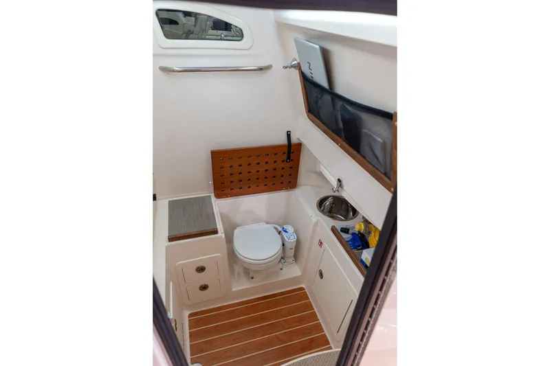 Slide: The Image of 2026 Grady-White Canyon 306 boat interior with compact bathroom and wooden flooring. - 10