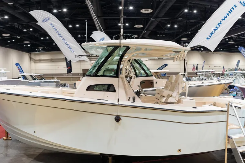 Slide: The Image of 2026 Grady-White Canyon 306 boat displayed at an indoor exhibition with branded flags. - 3