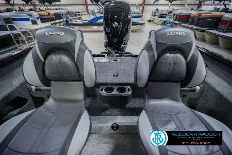 Slide: The Image of 2026 Lund 1775 Impact XS boat interior with dual seats and motor in showroom. - 19