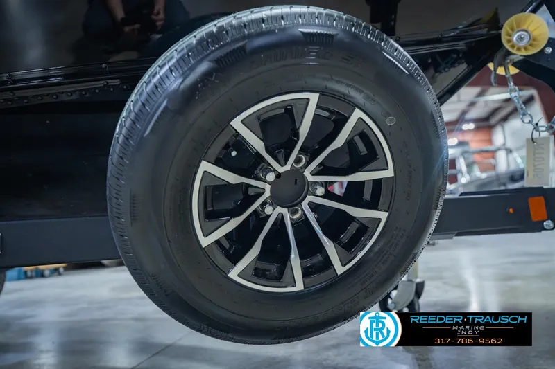 Slide: The Image of Close-up of a 2026 Lund 1775 Impact XS trailer wheel in a showroom setting. - 64