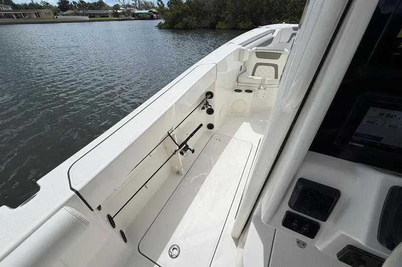 Slide: The Image of 2020 World Cat 295 CC boat interior with fishing rod holders on a calm waterway. - 15