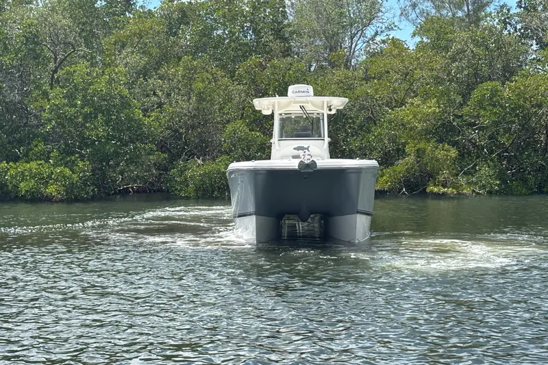Slide: The Image of 2020 World Cat 295 CC boat navigating through calm waters near lush greenery. - 3