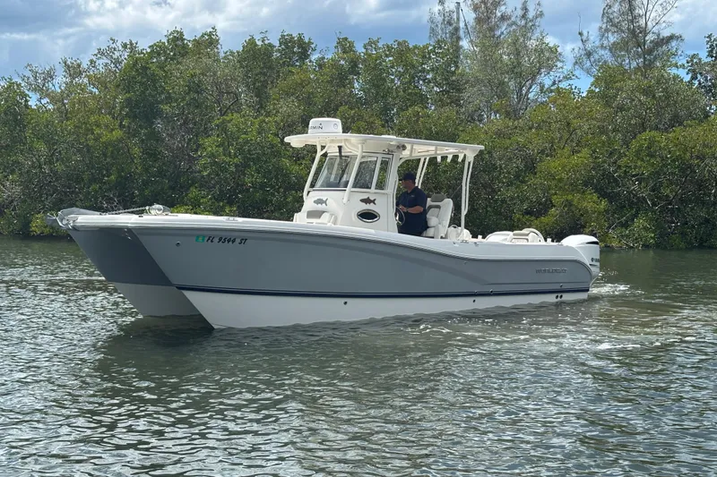 Slide: The Image of 2020 World Cat 295 CC boat cruising on a calm river with lush greenery. - 4