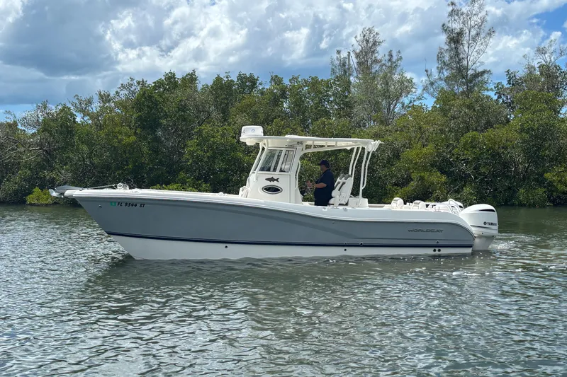 Slide: The Image of 2020 World Cat 295 CC boat on calm water, surrounded by lush greenery. - 5