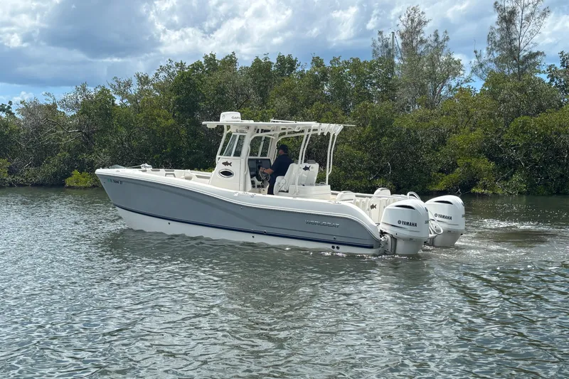 Slide: The Image of 2020 World Cat 295 CC boat cruising on a calm river with lush greenery. - 6