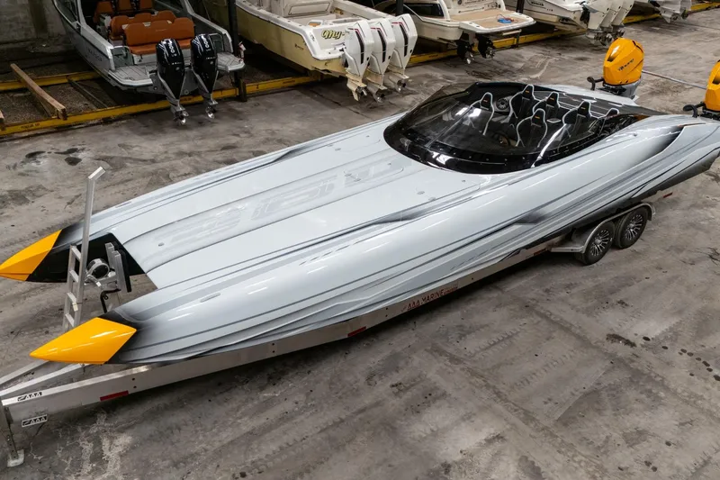 The Image of 2026 Doug Wright 36 powerboat with sleek design and yellow accents on trailer in warehouse. - 0