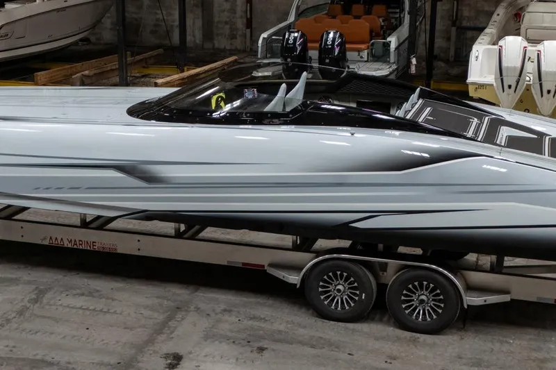 Slide: The Image of 2026 Doug Wright 36 powerboat on trailer in a showroom, showcasing sleek design and twin engines. - 2