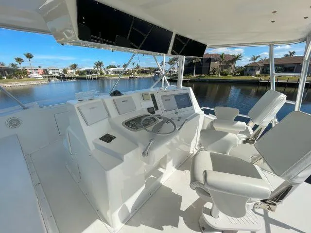 Slide: The Image of 1999 Viking 50 Convertible yacht helm with modern controls and seating, overlooking a serene waterfront. - 12