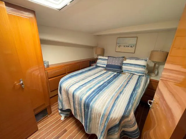 Slide: The Image of 1999 Viking 50 Convertible yacht bedroom with striped bedding and wooden cabinetry. - 37