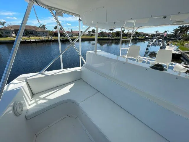 Slide: The Image of 1999 Viking 50 Convertible yacht interior with white seating, docked by a scenic canal. - 8