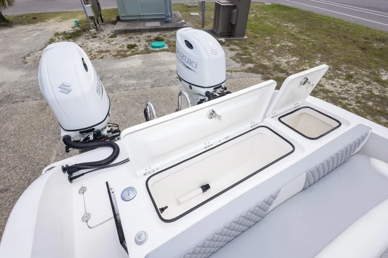 Slide: The Image of 2022 Twin Vee 240 GFX CC boat with dual Suzuki outboard motors and open storage compartments. - 15
