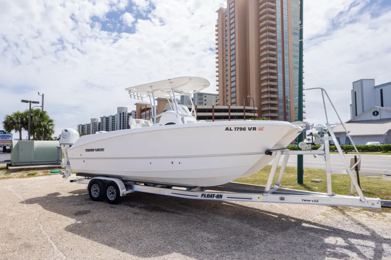 Slide: The Image of 2022 Twin Vee 240 GFX CC boat on trailer, urban background, partly cloudy sky. - 2