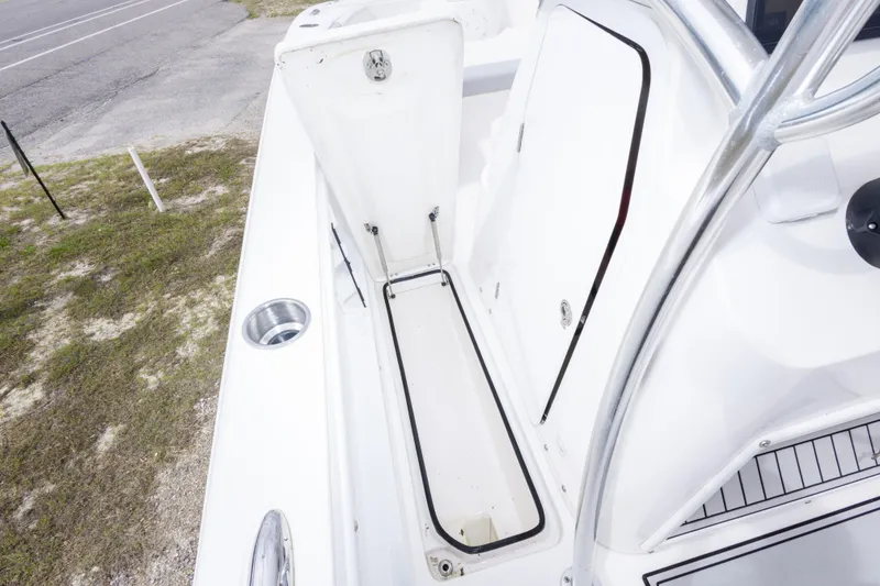 Slide: The Image of 2022 Twin Vee 240 GFX CC boat storage compartment with open hatch and cup holder. - 24