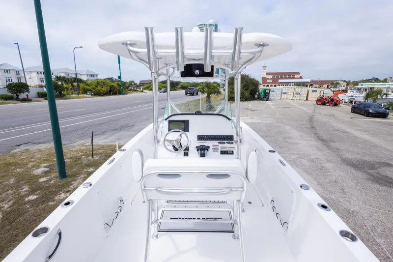 Slide: The Image of 2022 Twin Vee 240 GFX CC boat interior with steering console and seating, parked near a road. - 35