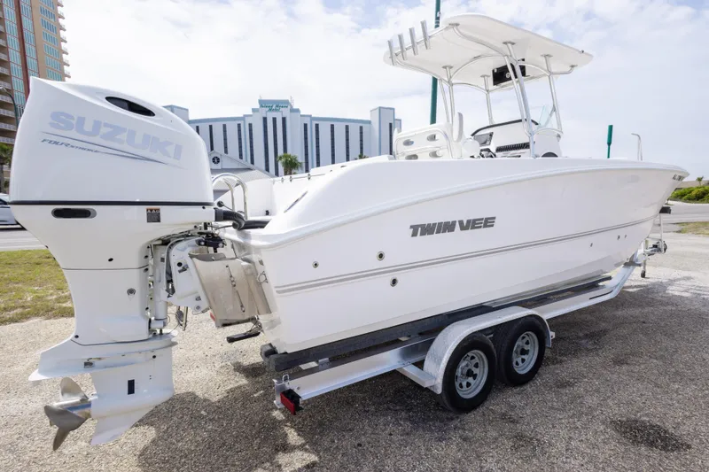 Slide: The Image of 2022 Twin Vee 240 GFX CC boat with Suzuki engine on trailer, parked near buildings. - 5
