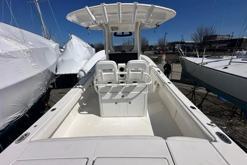 Slide: The Image of 2021 Regulator 28 Forward Seating boat, white interior, docked outdoors under clear sky. - 19