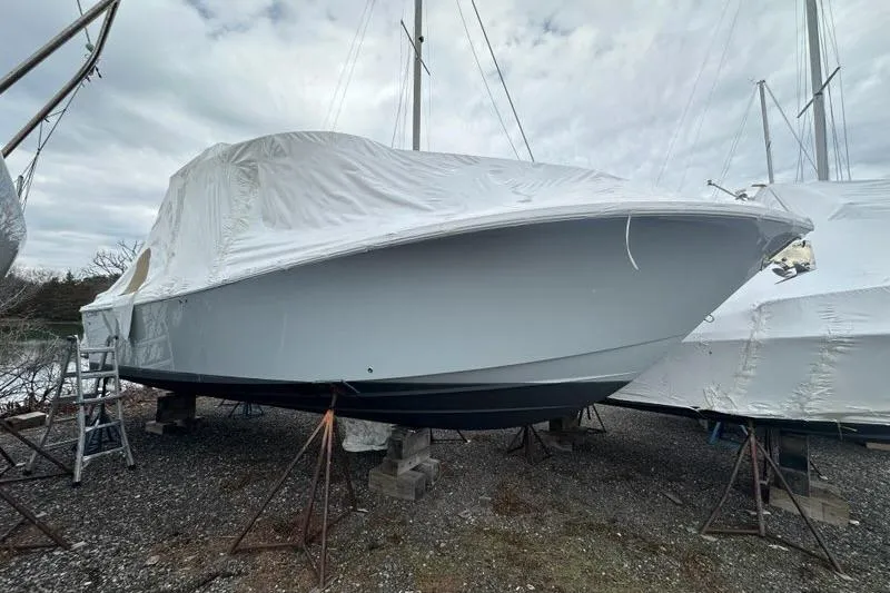 Slide: The Image of 2021 Regulator 28 Forward Seating boat covered and stored on land. - 2