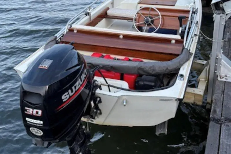 Slide: The Image of 1988 Boston Whaler 130 Super Sport with Suzuki 30 outboard motor docked on water. - 2