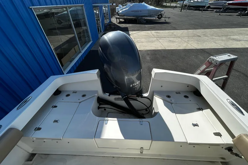 Slide: The Image of 2019 Parker 21 Special Edition boat with 150 HP outboard motor, docked near blue building. - 6