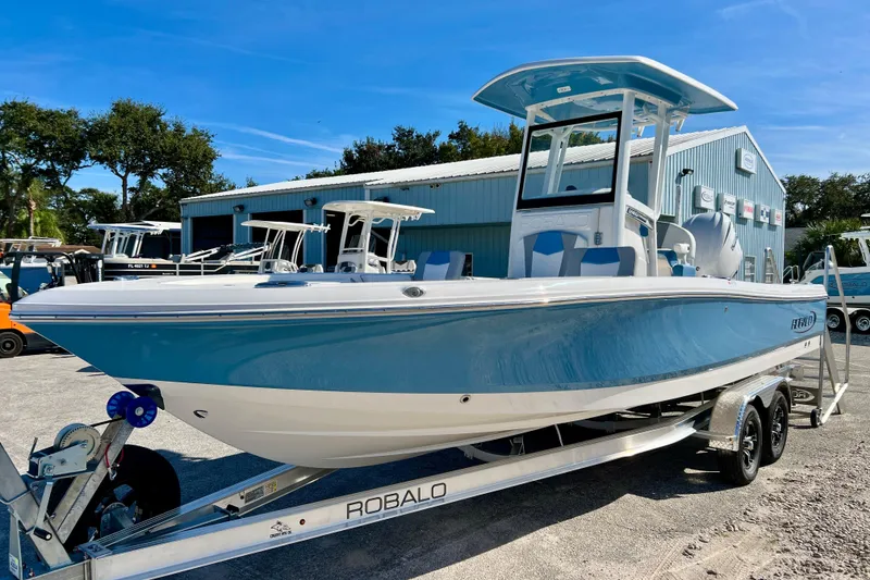 Slide: The Image of 2026 Robalo 246 Cayman boat on trailer, blue and white, parked outdoors. - 4