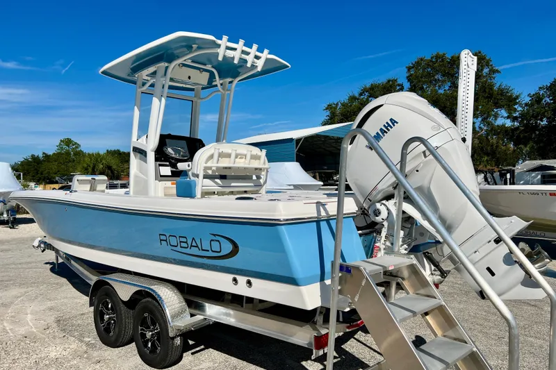 Slide: The Image of 2026 Robalo 246 Cayman boat with Yamaha engine, parked on a trailer under clear blue sky. - 6