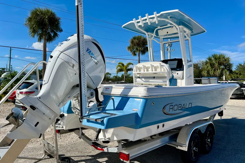 Slide: The Image of 2026 Robalo 246 Cayman boat with Yamaha engine, parked on a trailer under clear blue skies. - 8