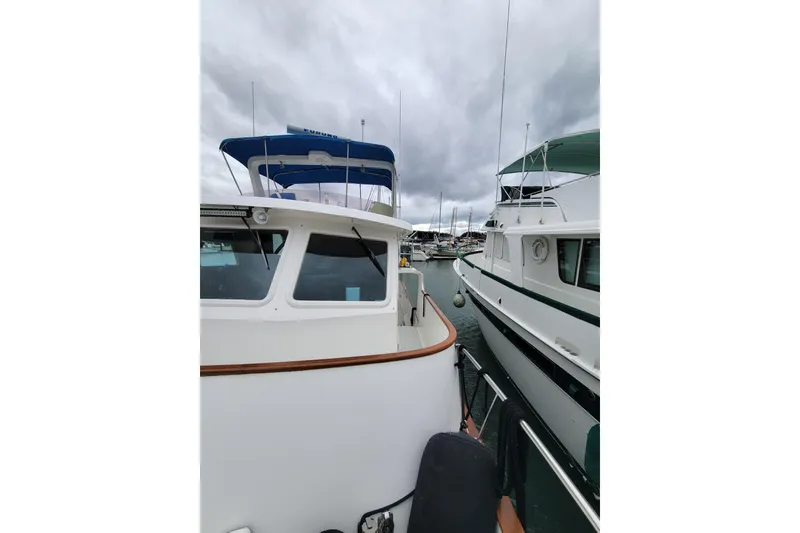 Slide: The Image of 2001 DeFever Pilothouse yacht docked beside another boat under cloudy skies. - 10