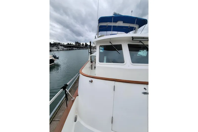 Slide: The Image of 2001 DeFever Pilothouse yacht docked, showcasing sleek design and spacious deck under cloudy skies. - 11