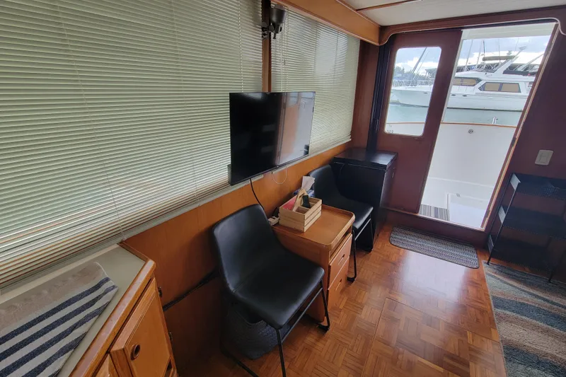Slide: The Image of 2001 DeFever Pilothouse interior with seating, TV, and view of marina through glass doors. - 23