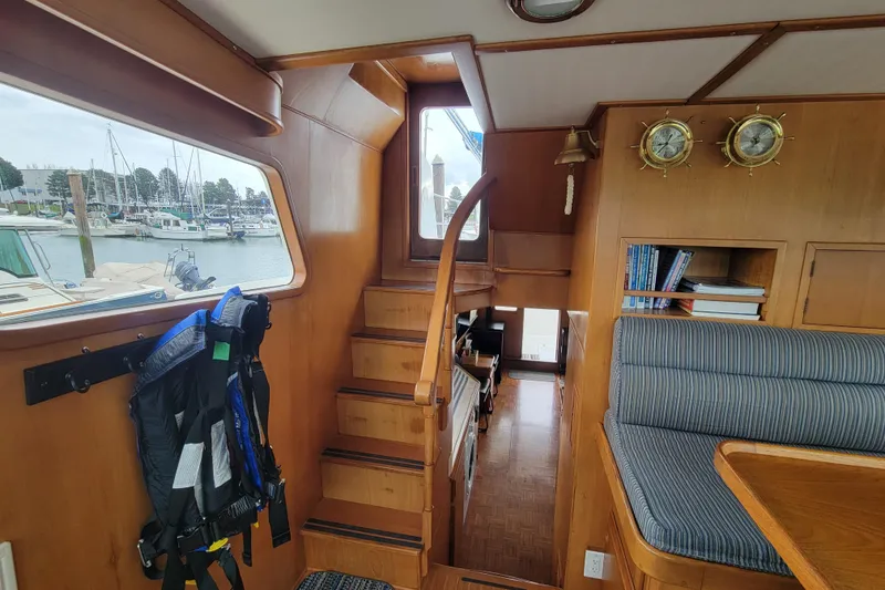 Slide: The Image of Interior of 2001 DeFever Pilothouse with wooden stairs, seating, and marina view. - 25