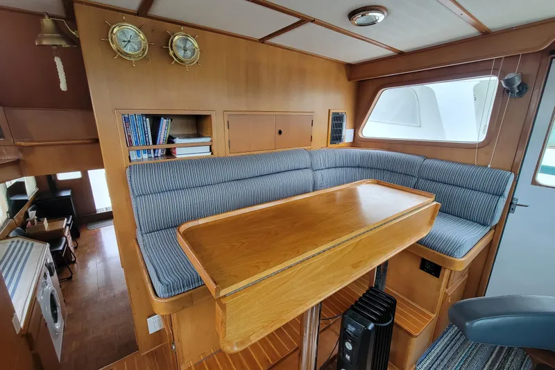 Slide: The Image of 2001 DeFever Pilothouse interior with cozy seating, wooden table, and nautical decor. - 26