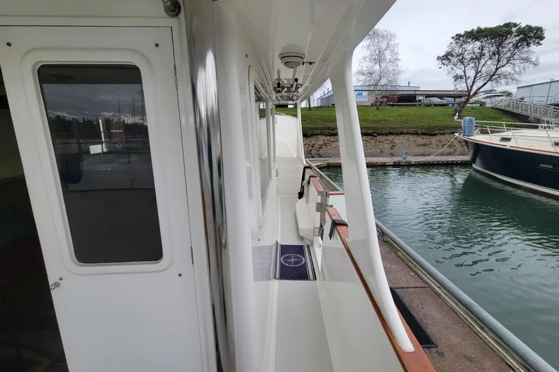 Slide: The Image of 2001 DeFever Pilothouse yacht docked, showcasing side deck and marina view. - 37