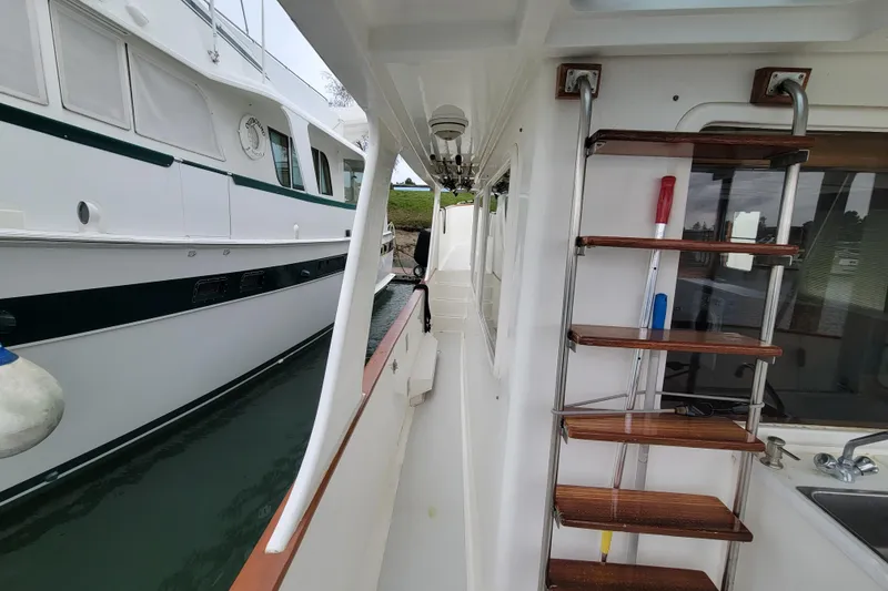 Slide: The Image of 2001 DeFever Pilothouse yacht exterior with wooden steps and docked alongside another vessel. - 38