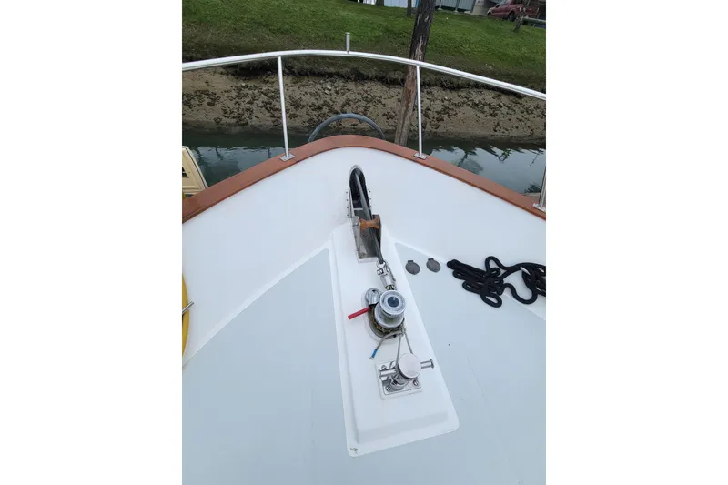 Slide: The Image of 2001 DeFever Pilothouse boat deck with anchor and ropes, docked by grassy shore. - 8
