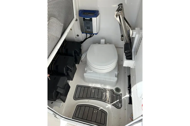 Slide: The Image of Interior of 2021 Sea Hunt Ultra 255 SE boat featuring a compact marine toilet setup. - 10
