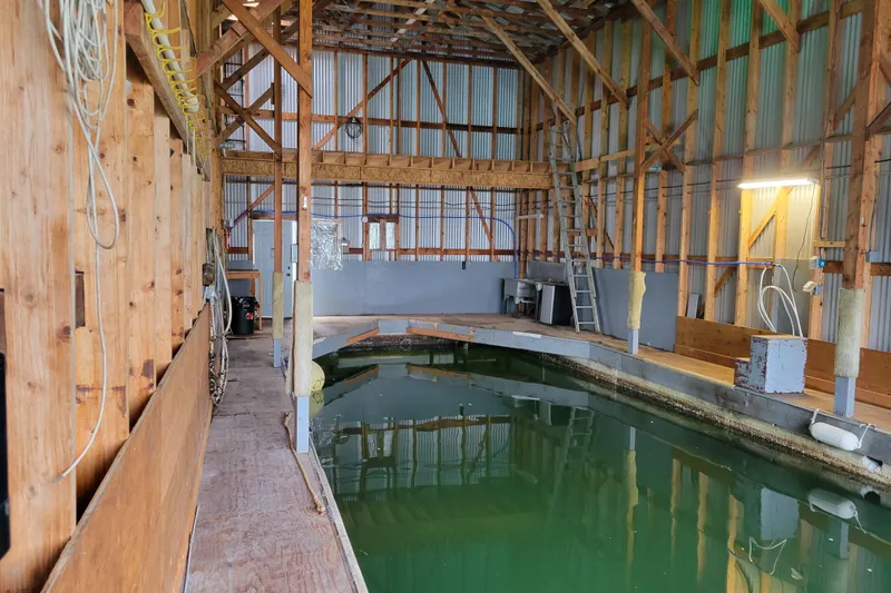 Slide: The Image of Interior of a custom 2015 boathouse with wooden beams and a water channel. - 3