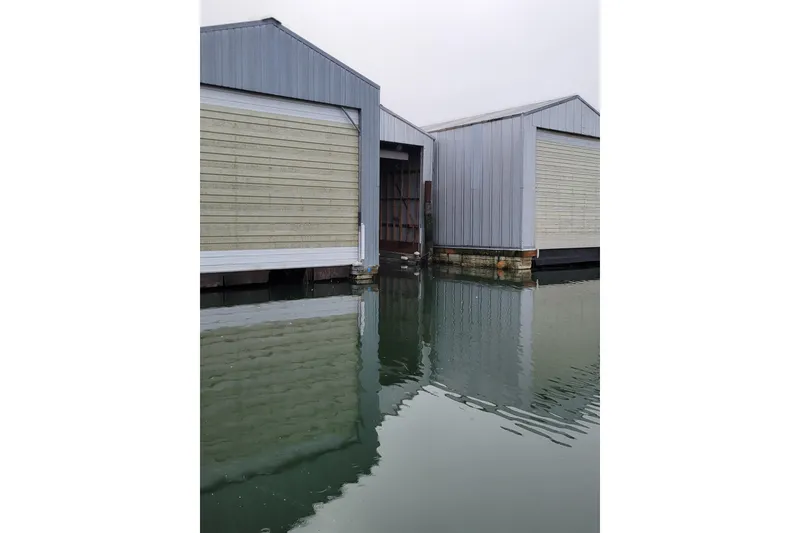 Slide: The Image of Custom 2015 boathouse with reflective water, featuring metal siding and closed doors. - 6