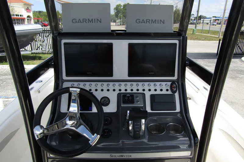 Slide: The Image of 2023 ShearWater 260 Carolina Flare boat dashboard with dual Garmin displays and steering wheel. - 23