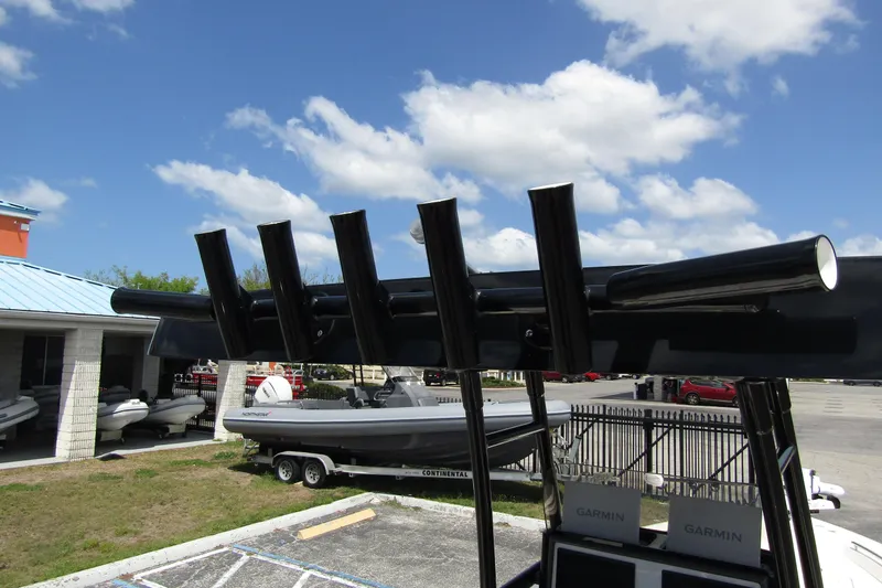 Slide: The Image of 2023 ShearWater 260 Carolina Flare boat with rod holders, parked outdoors under blue sky. - 27