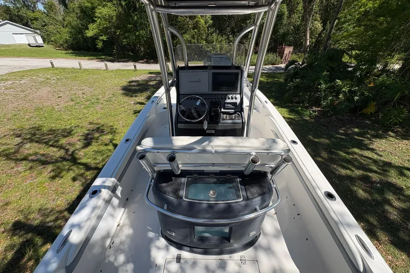 Slide: The Image of 2018 ShearWater 26 Carolina boat interior with console and seating, surrounded by greenery. - 14